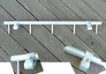 A metal coat rack with multiple pegs and clamps, laid out on a wooden surface.