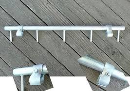 A metal coat rack with multiple pegs and clamps, laid out on a wooden surface.